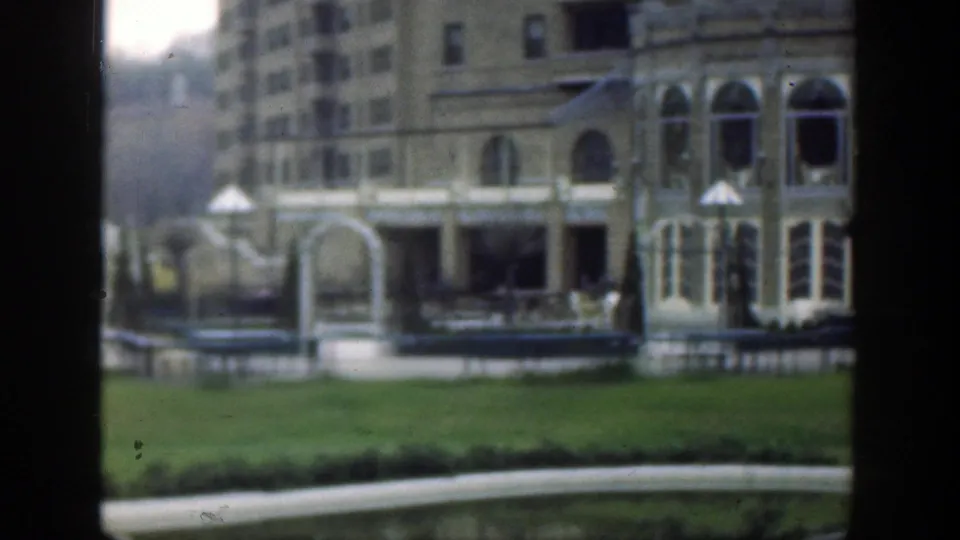 1949 Cincinnati frame of a stone building section with arched entrance, arched windows, open lawn, path, and formal landscaping.