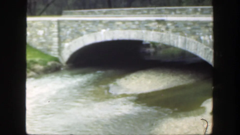 8mm home-movie frame from Cincinnati in 1949 showing the bridge arch over water and a exposed gravel bar.