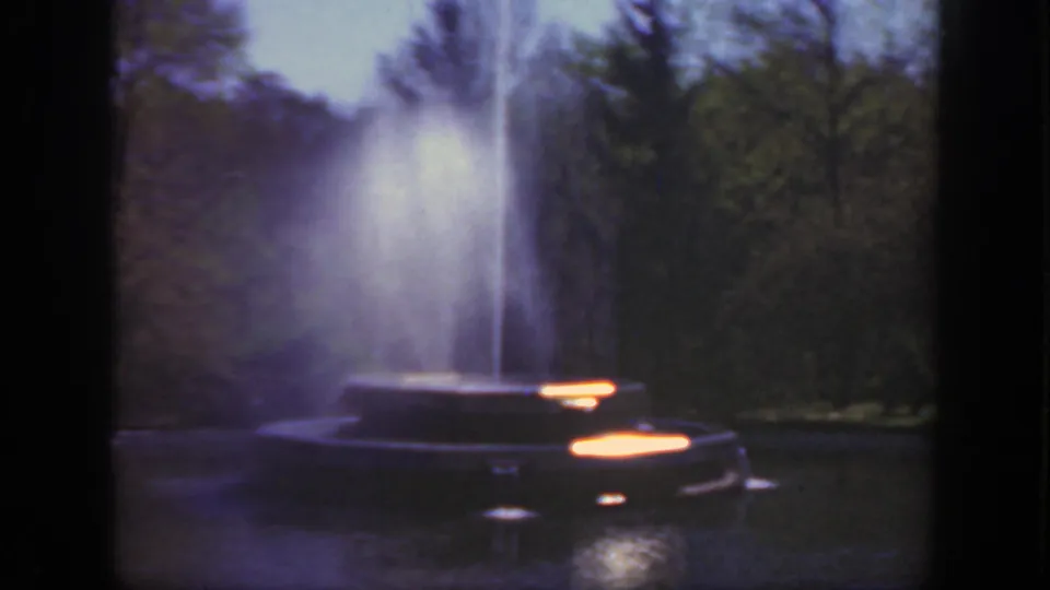 1949 Cincinnati home-movie still showing the fountain basin, vertical spray, shaded trees, and bright outdoor color exposure.