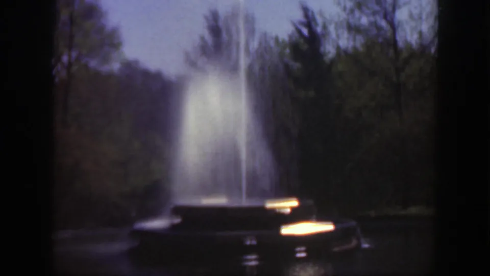 1949 Cincinnati frame showing the fountain behind trees, with a dark object partly visible near the spray.