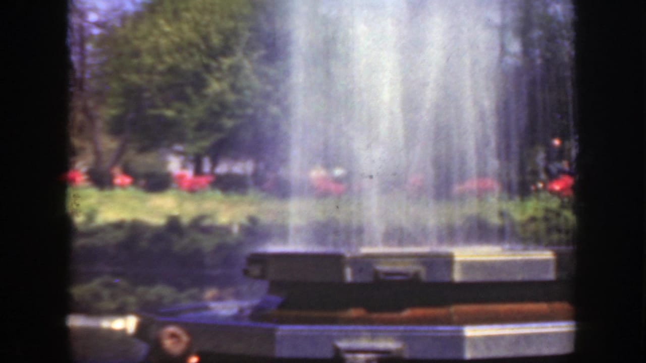 Fountain basin and high water spray seen through dark 8mm frame edges.