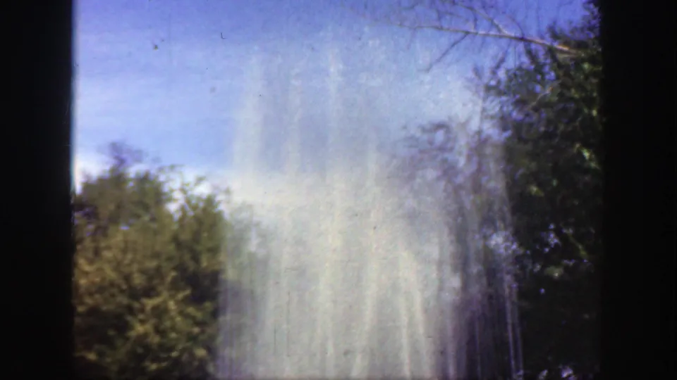 A 1949 Cincinnati 8mm view frames the upper fountain plume against blue sky, with surrounding park trees and dark film borders.