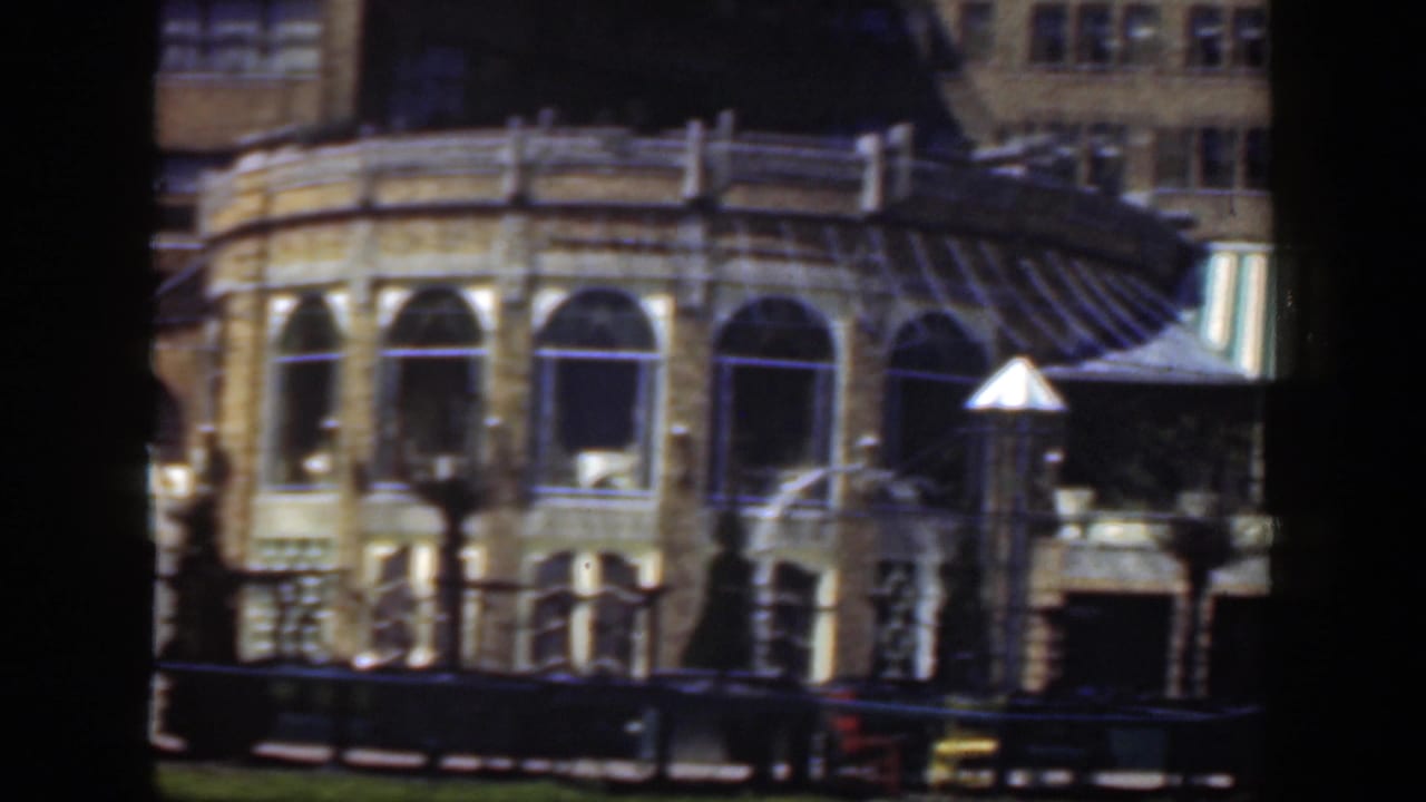 1949 Cincinnati 8mm frame showing an arched masonry facade, striped awning, benches and lawn from a visitor viewpoint.