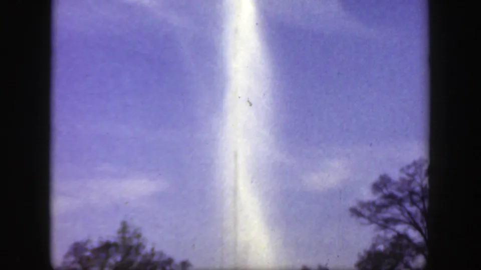 1949 Cincinnatti, Ohio 8mm frame emphasizing the tall fountain spray, with treetops and a blue sky visible around it.