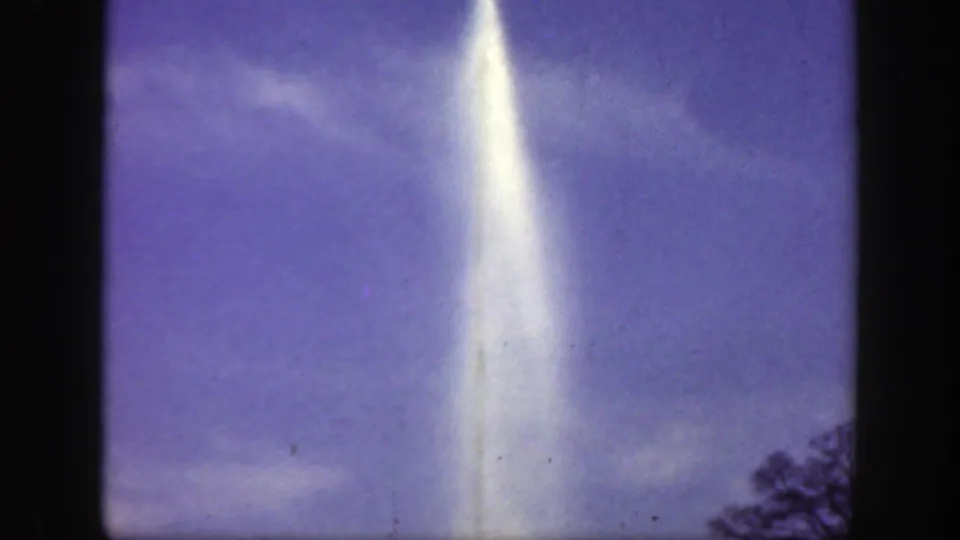 1949 8mm home-movie frame from Cincinnati, Ohio metadata showing a tall white water plume rising against a purple-blue sky with faint clouds and slight film wear.