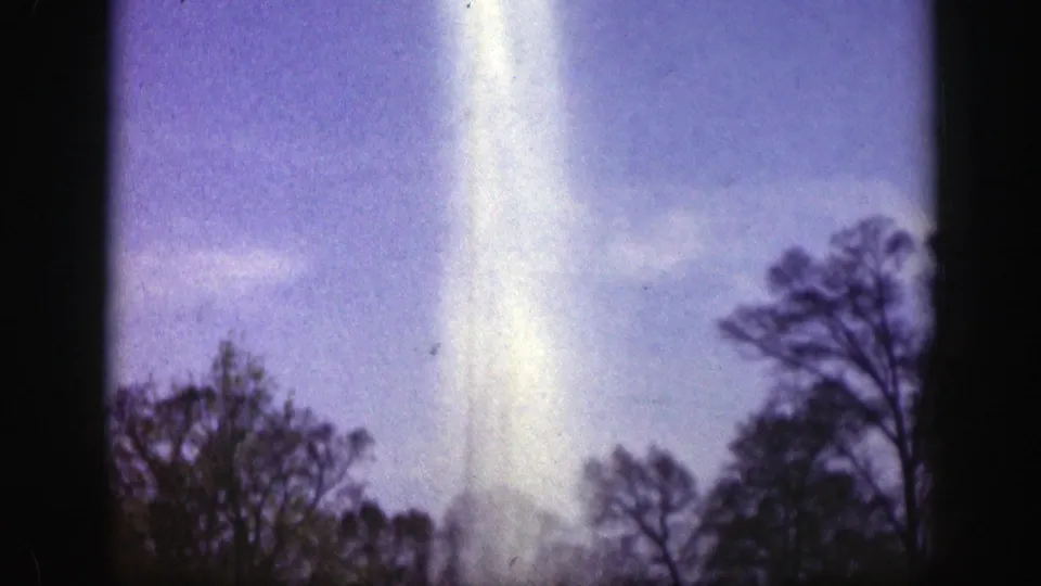 The water plume fills the center of the 1949 Cincinnati 8mm frame, rising above dark tree silhouettes under a blue-purple sky with visible film texture.
