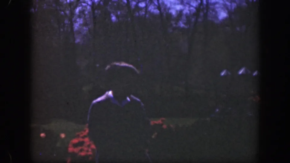 The shadowed subject continues walking toward the 8mm camera in a dim 1949 Cincinnati garden scene.