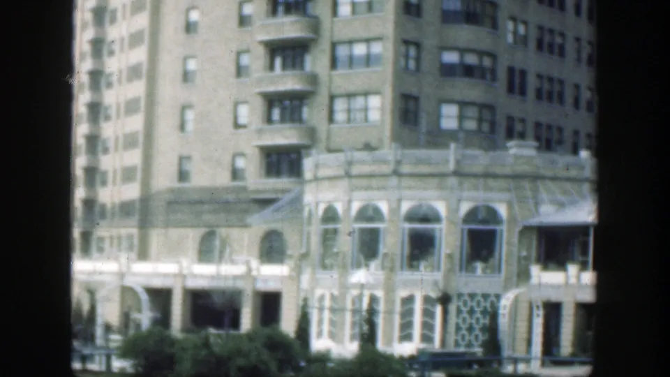 1949 Cincinnati 8mm frame showing an ornate building facade with arched windows, decorative lower panels, shrubs, and upper residential-style windows.