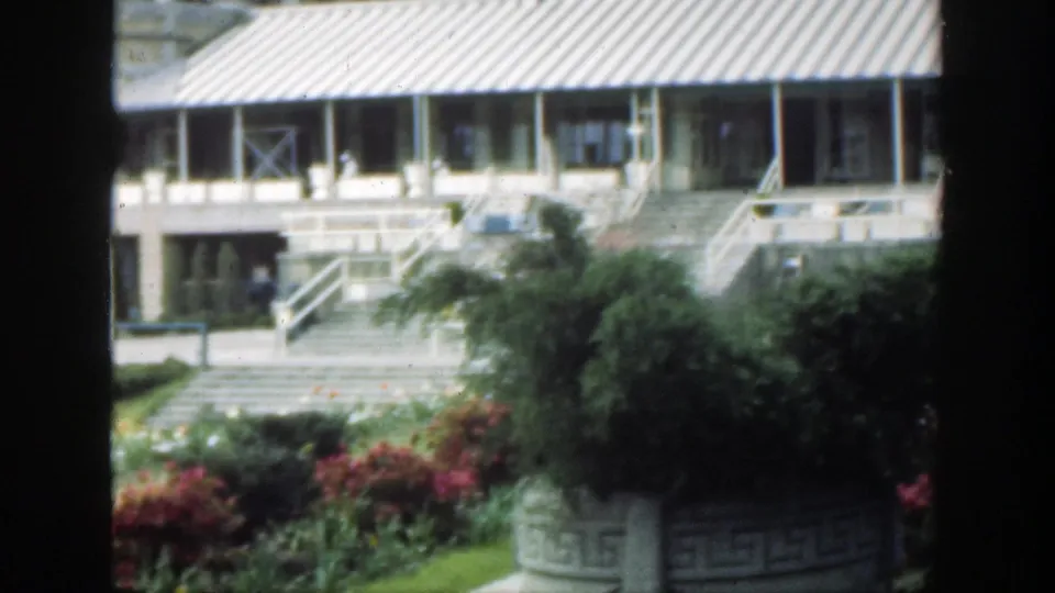 1949 Cincinnati home-movie view of a landscaped garden and building facade, partially obscured by dark window-like borders.