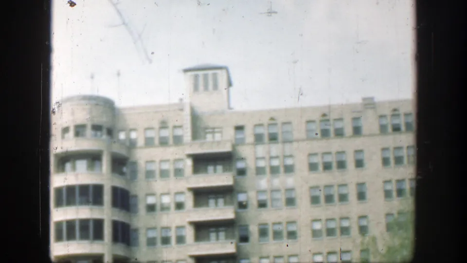 1949 8mm view of a Cincinnati apartment or office facade with a rounded bay, balconies, repeated windows, and rooftop detail.