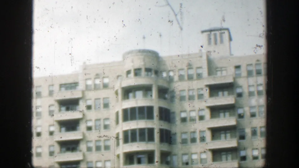 Late 1940s Cincinnati building exterior with curved window bay, balconies, repeated windows, and visible 8mm dust and scratches.