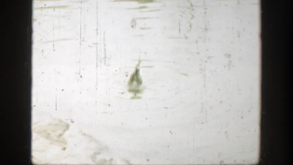 Faded 1949 Cincinnati 8mm frame with scratches, dust, and a faint bird-like form above a barely visible water setting.
