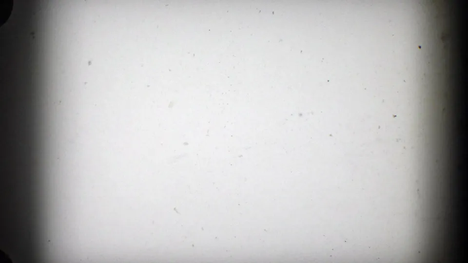 A pale, mostly blank 8mm frame showing dust, slight discoloration, and dark rounded edge shadows.