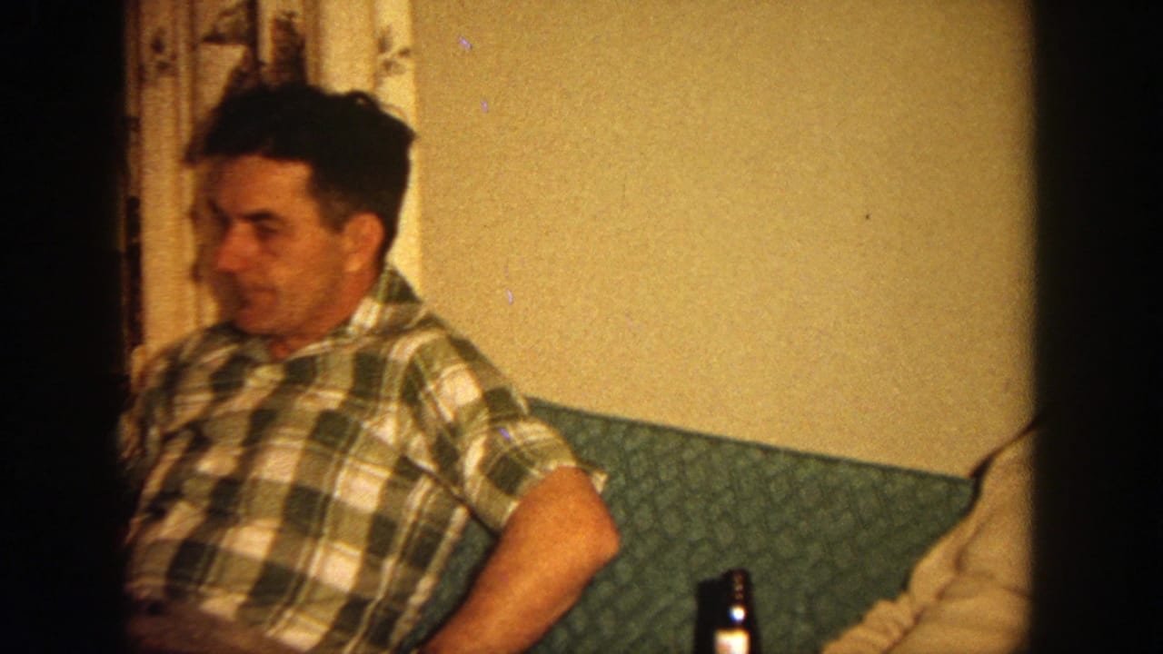 A man in a plaid shirt sits on a green couch beside another man.