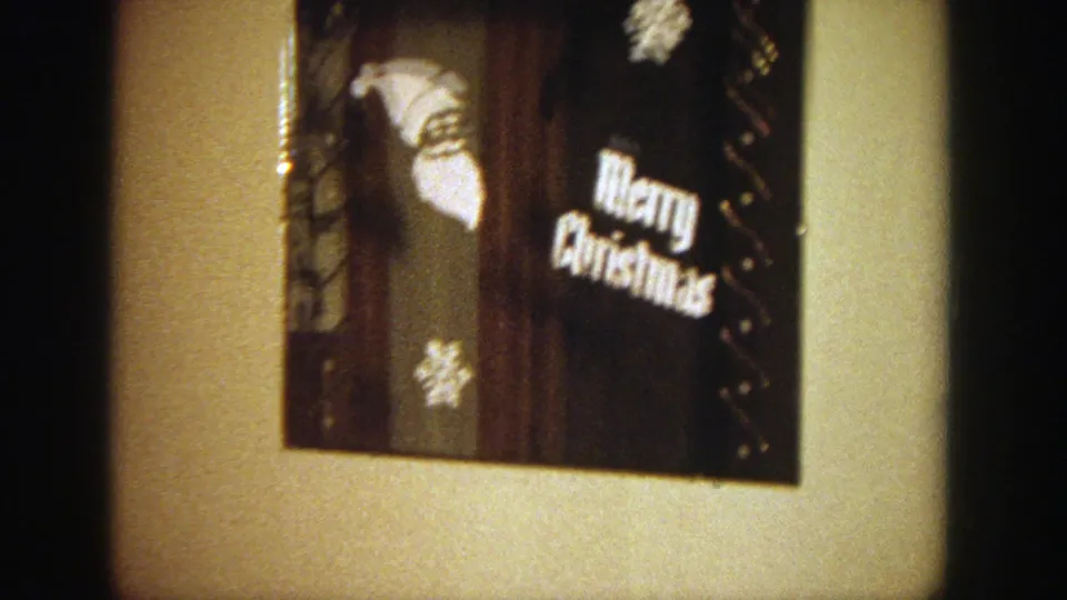 A Merry Christmas decoration hangs on the wall of the private living room, with couch fabric and a partial figure at the edge.