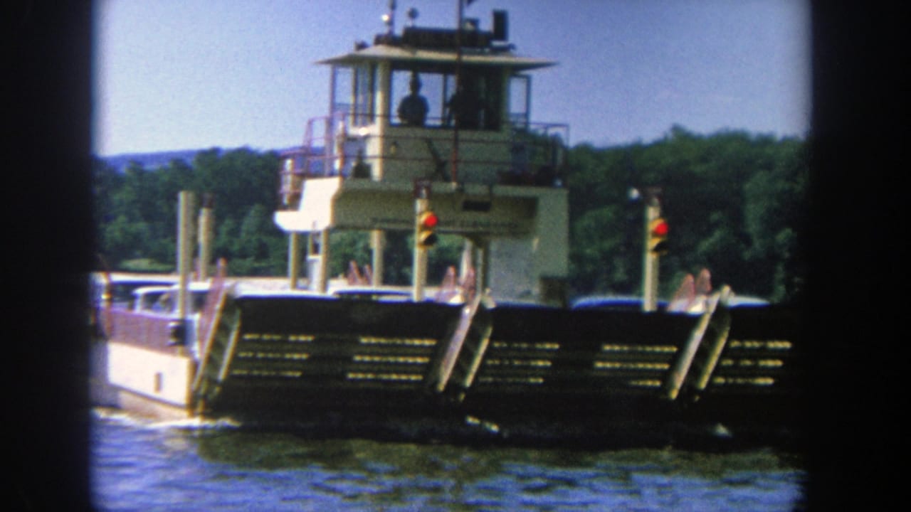 Ferry centered on the river with control tower, railings, and signal lights visible.