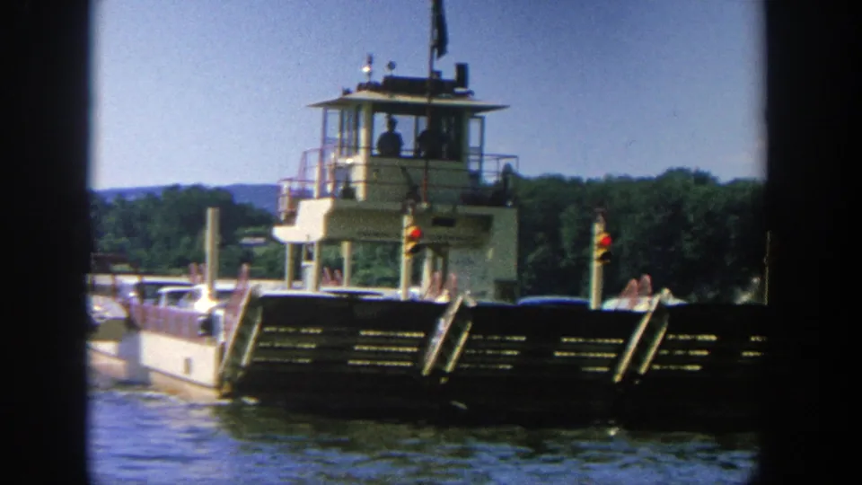 1964 Wisconsin frame of a river ferry under clear sky, with signal lights and the raised control cabin visible above the hull.