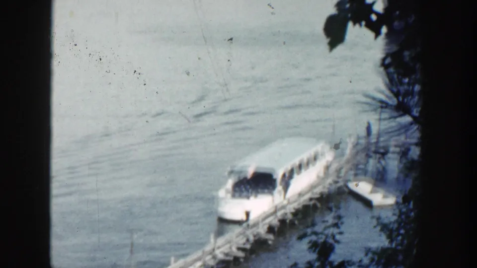 The clearest frame shows the white tour boat at the dock on calm Wisconsin lake water, with faint passengers or figures aboard.