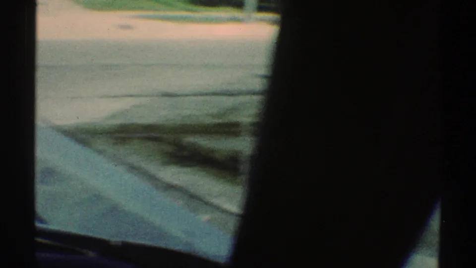 Motion-blurred 8mm view of pavement, curb, and vehicle interior shadow during the Woodland Hills street drive.