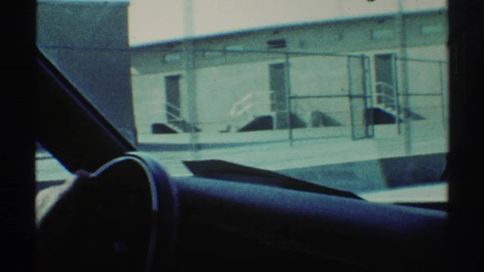 1969 Woodland Hills view from inside a car toward a low school building with railings, doors, and windows.