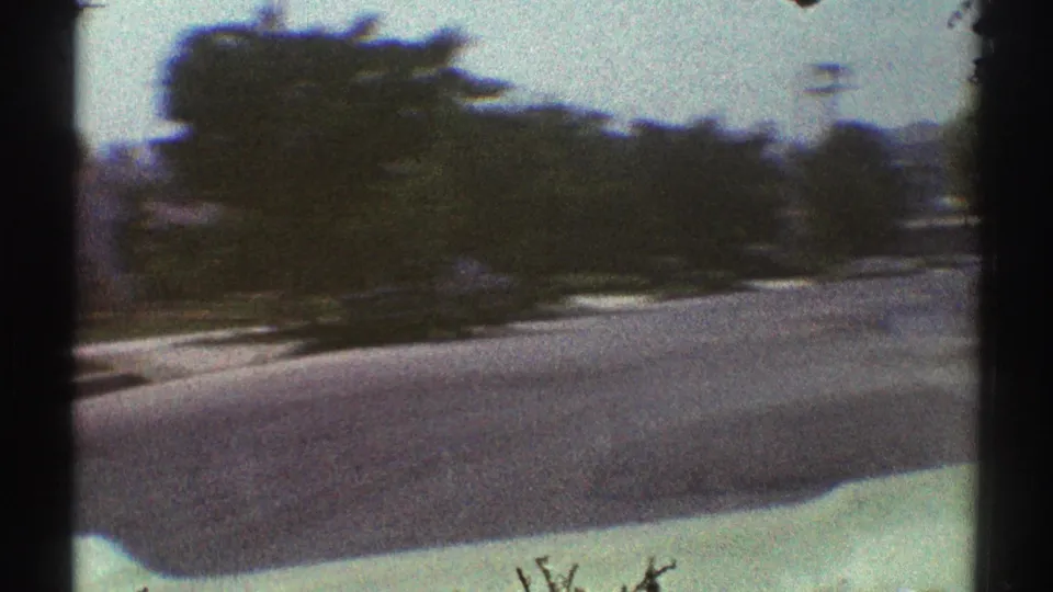 A closer 1969 home-movie view of the Woodland Hills street shows the road surface, planted edges, trees, and soft motion blur.