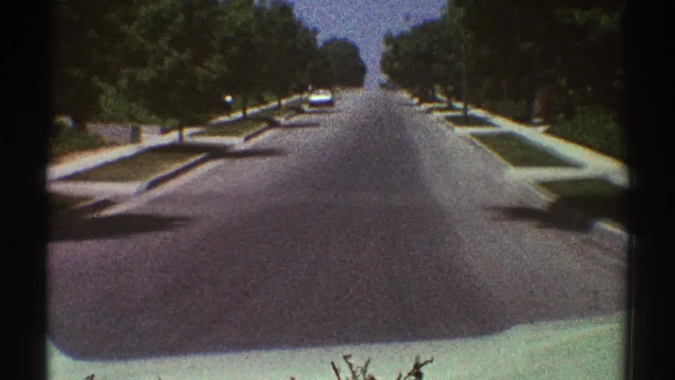 A forward-facing 1969 Woodland Hills street view shows a white car approaching along a broad residential road.