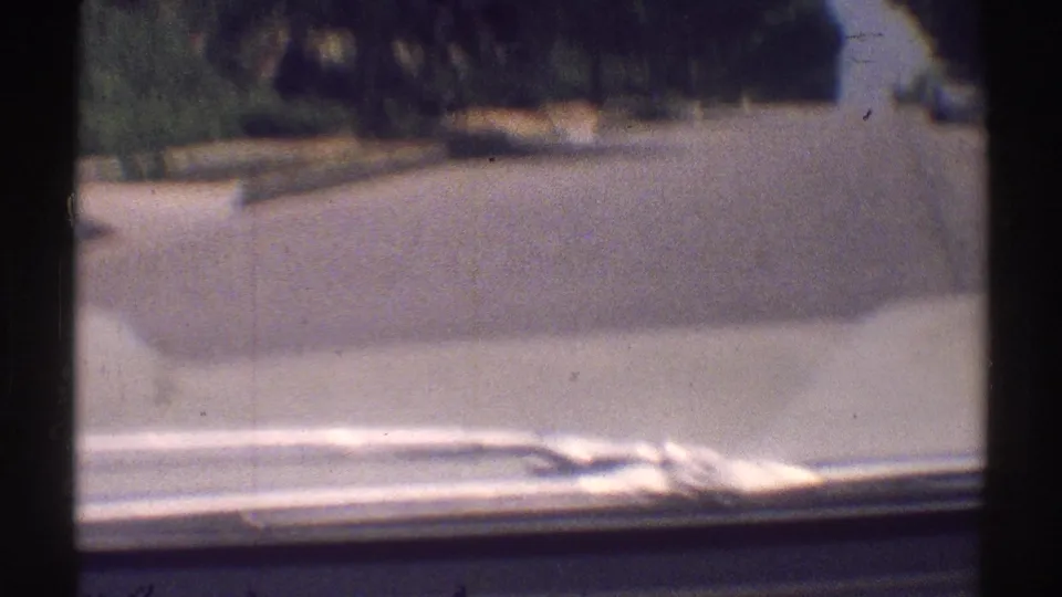 Woodland Hills residential road in 1969, seen through a washed, sunlit 8mm frame with curbside greenery and film borders.