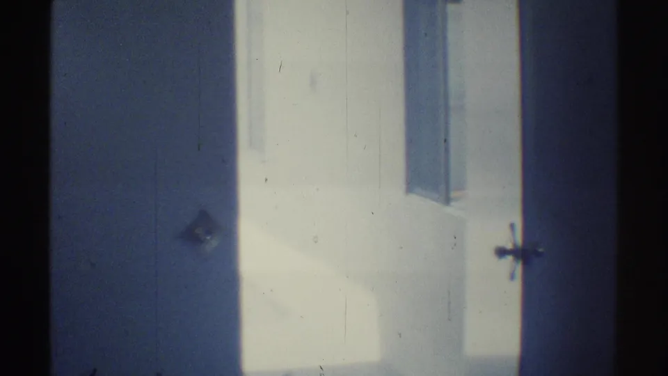 1969 Woodland Hills home-movie frame approaching a white garage or entry opening with shaded interior edges.