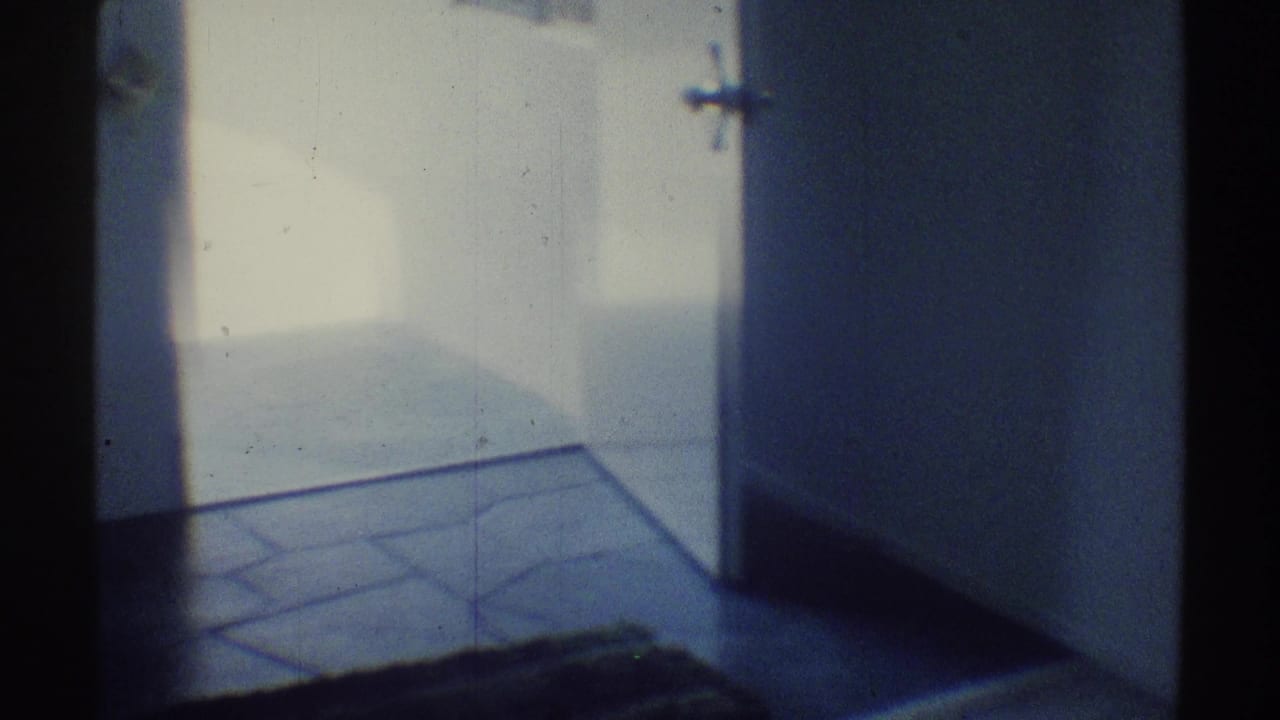 Doorway opening onto tiled entry flooring with white walls and a dark doormat.