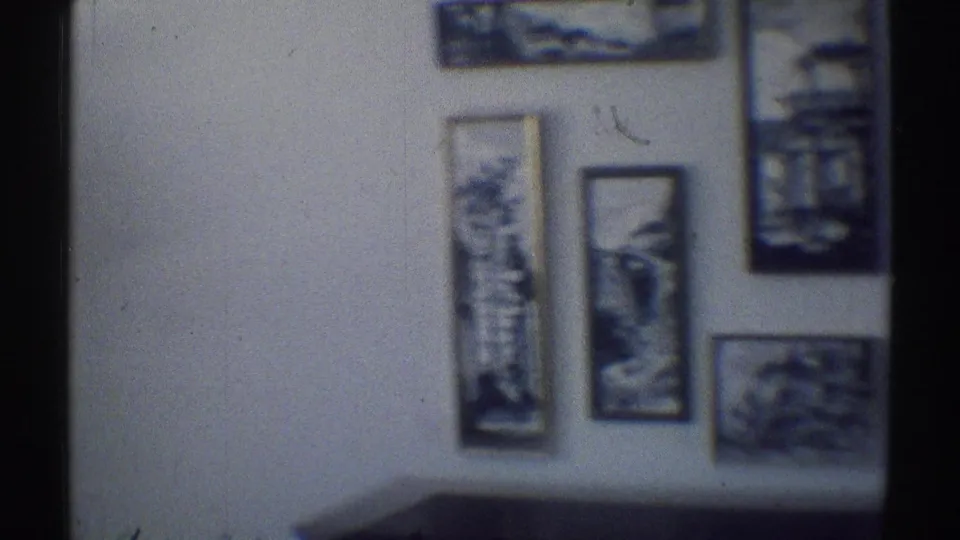 1969 Woodland Hills interior wall with several framed artworks and the top of dark furniture below.