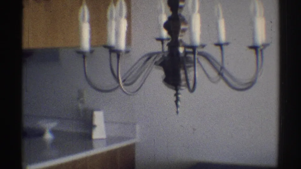 1969 Woodland Hills home-movie frame showing a candle-style chandelier above an interior counter area with wall surfaces and household fixtures behind it.