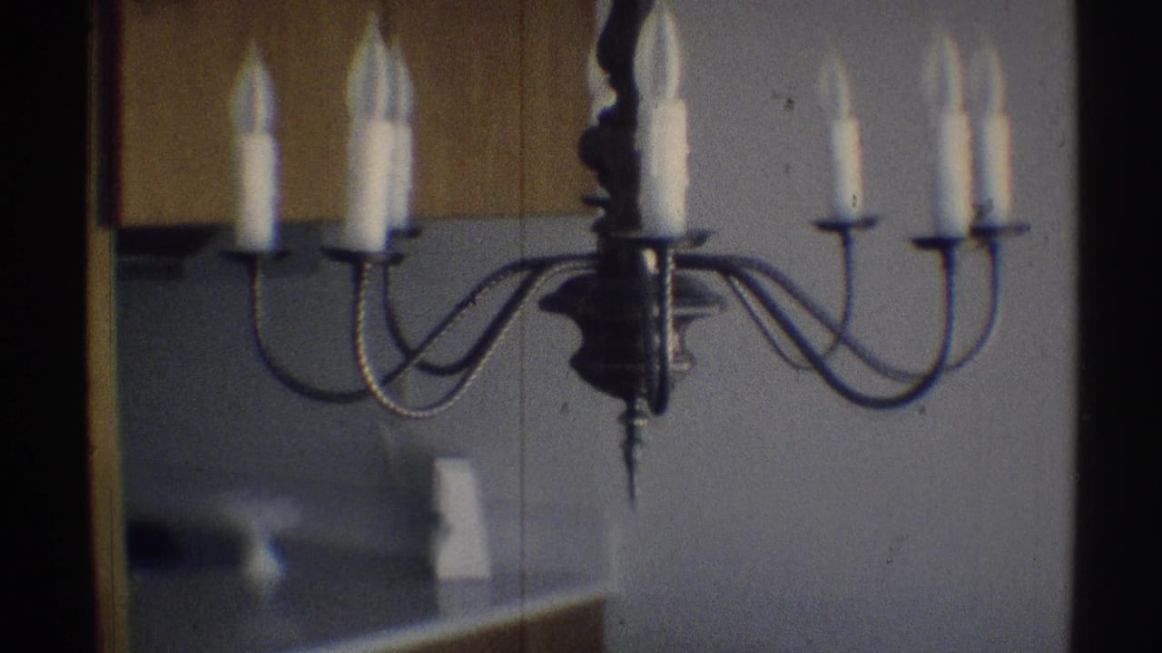 Wrought iron candle-style chandelier against a plain wall and wood cabinetry.