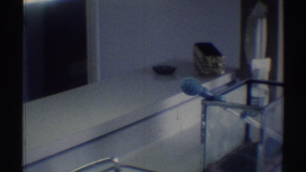 Dim bathroom counter with mirror, toiletries, and a blue grooming item in soft focus.