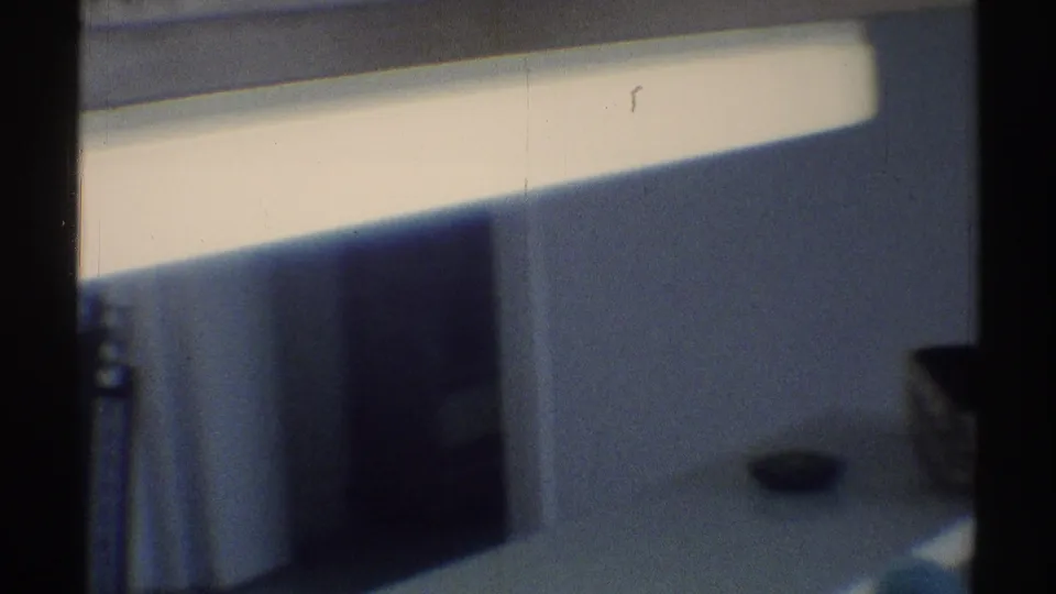Soft, blue-tinted 1969 Woodland Hills interior with a counter edge, wall, dark doorway area, and daylight band above.