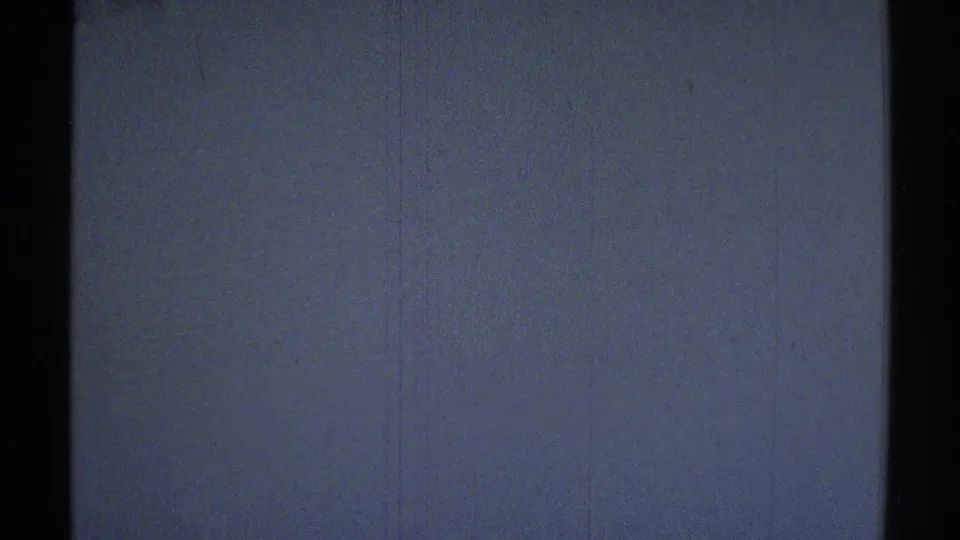 1969 Woodland Hills home-movie frame showing a dim interior wall and dark vertical doorway or frame with film grain visible.