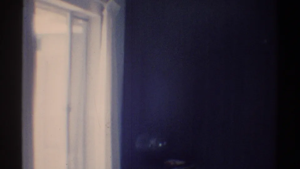 1969 Woodland Hills 8mm frame showing a bright open window, pale curtains, white trim, and a darkened interior wall.
