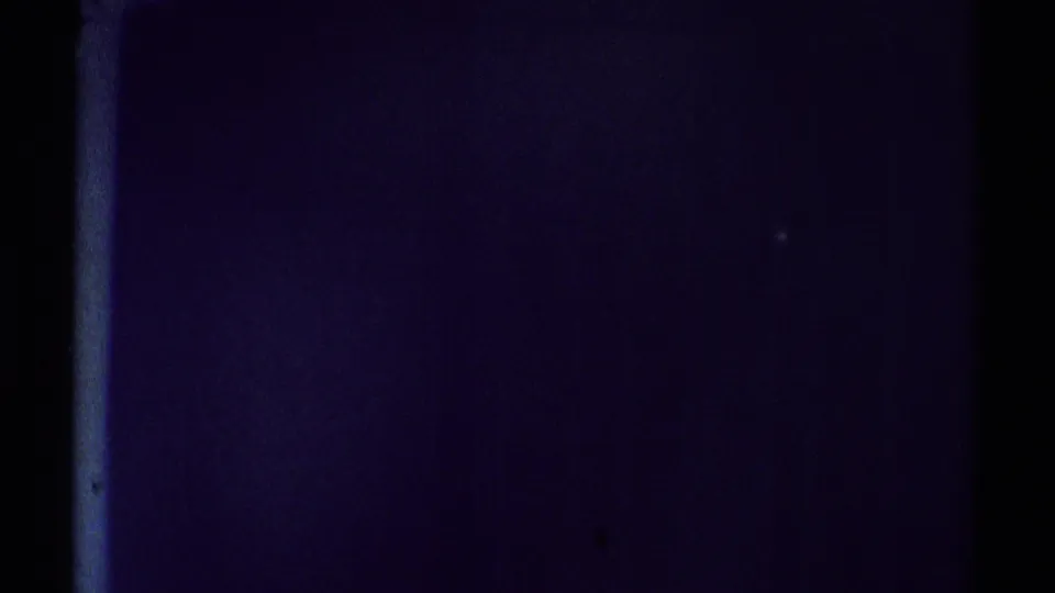 1969 Woodland Hills home-movie frame showing a dim interior surface, heavy purple shadow, and a slim bright vertical edge.