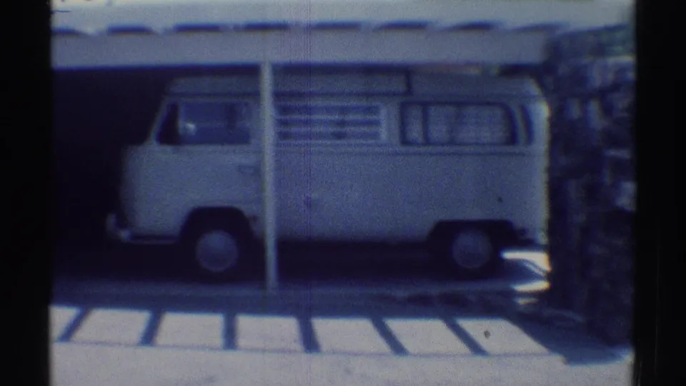 The white van remains parked under the carport, framed by driveway paving and a light Woodland Hills house exterior.