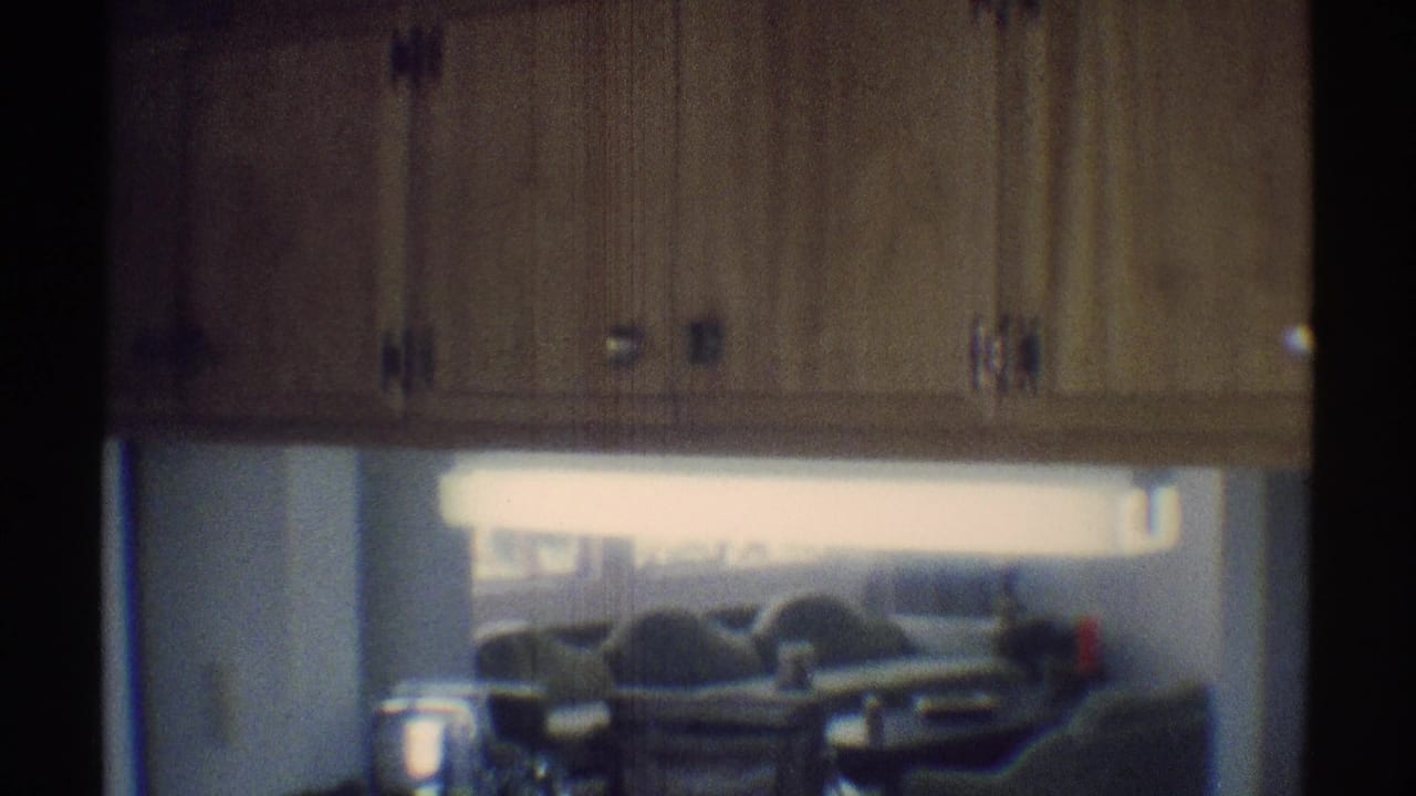 1969 Woodland Hills home-movie frame showing wood kitchen cabinetry and a counter, with a living room and couches in the background.