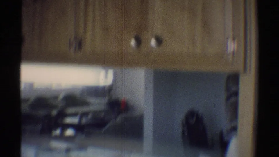 1969 Woodland Hills interior view looking from the kitchen toward couches near a bright living-room window.