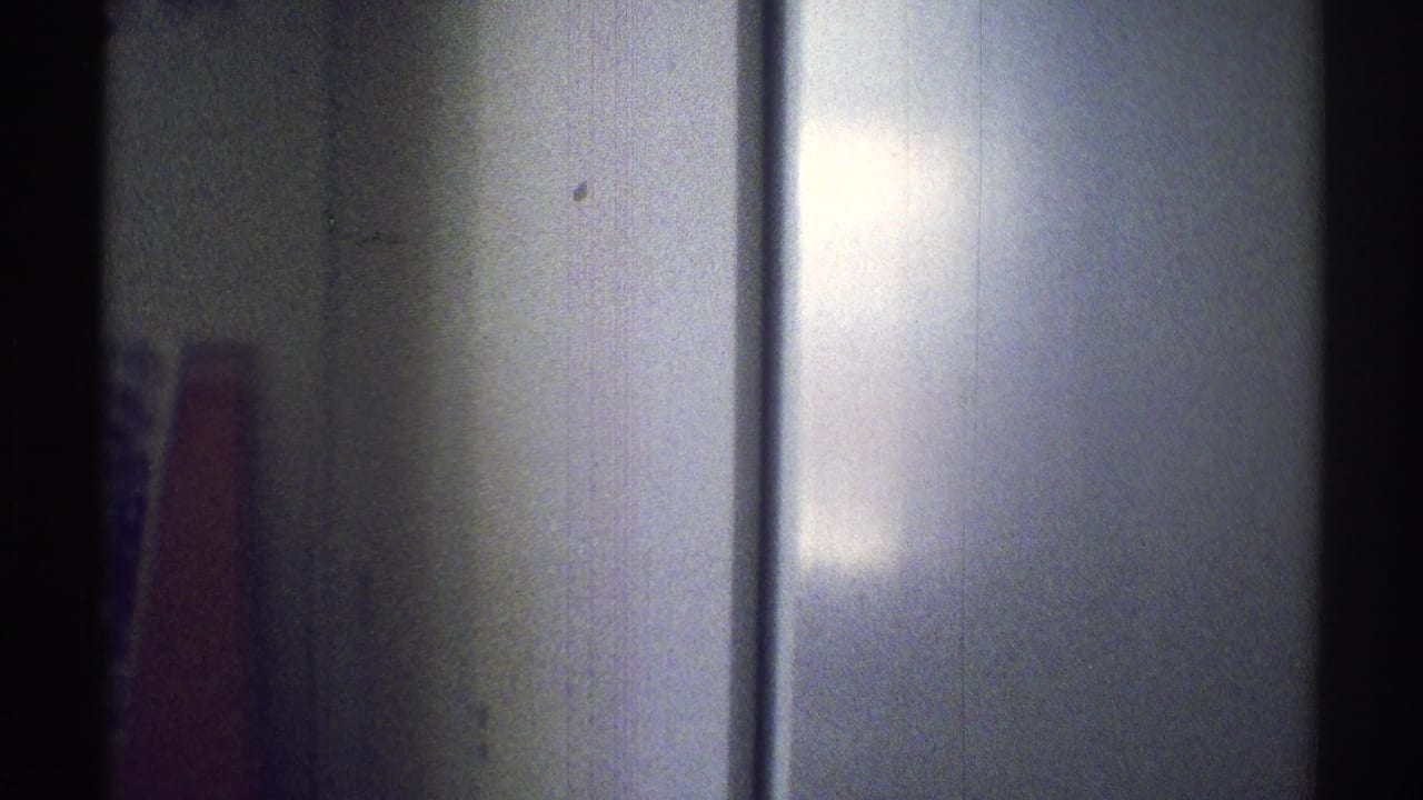 1969 Woodland Hills 8mm frame showing a shadowed interior wall and a partially visible red object near the left edge.