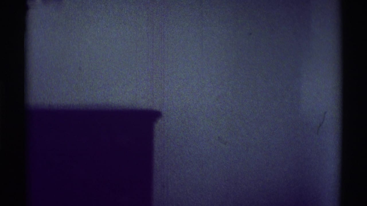 Dim wall and dark furniture silhouette with film-frame borders.