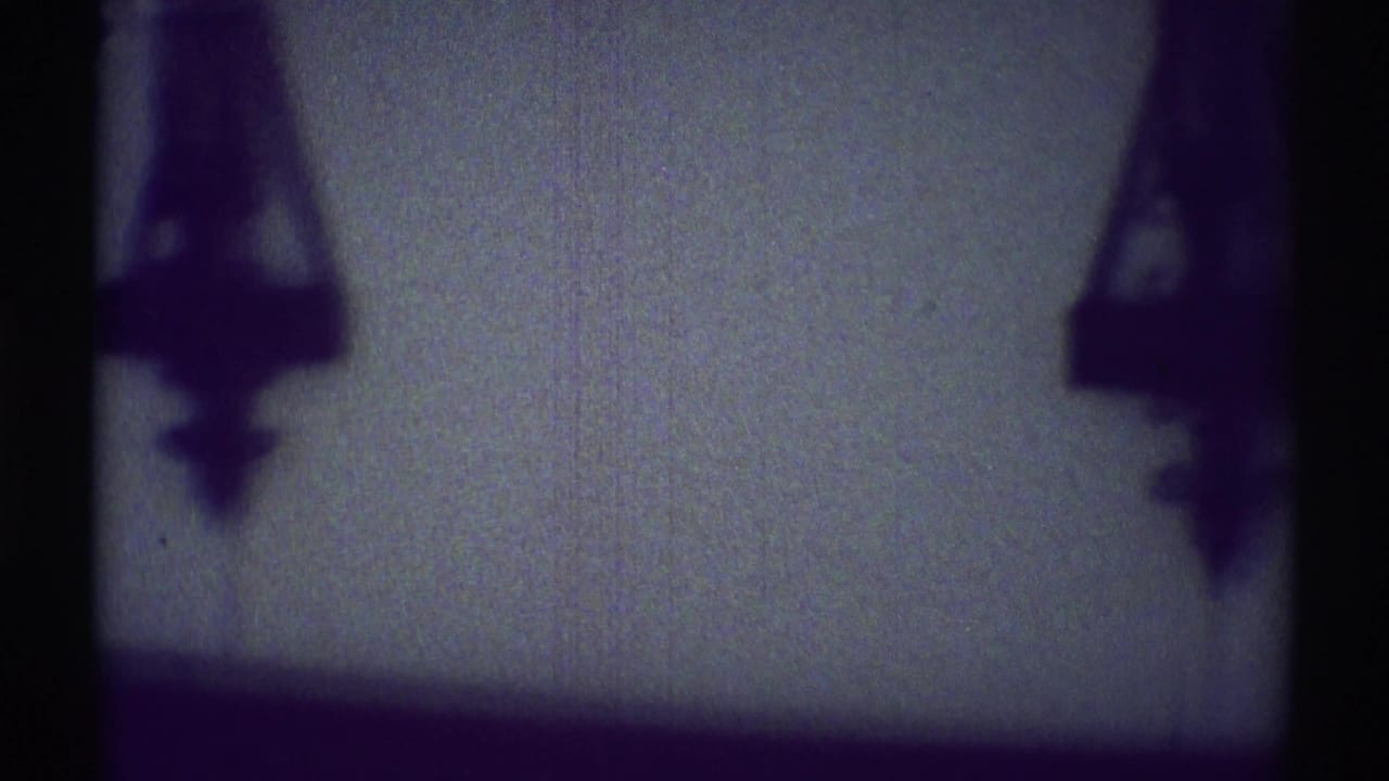 Dark hanging fixture silhouettes against a dim interior wall.