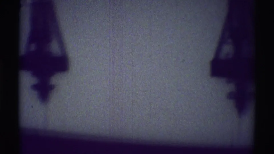 Hanging lamp or fixture shapes appear in silhouette against a dim bedroom wall in the Woodland Hills home movie.