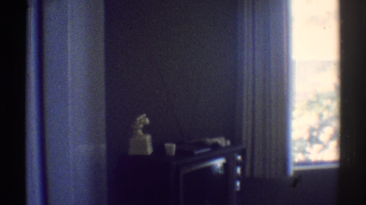 Dim bedroom view with doorway, window, small table, and white figurine.