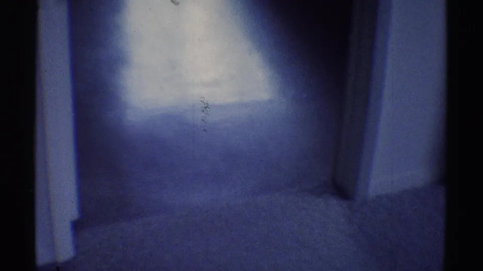 1969 Woodland Hills bedroom frame showing a doorway, blue interior wall, bright window spill, and mostly empty floor area.