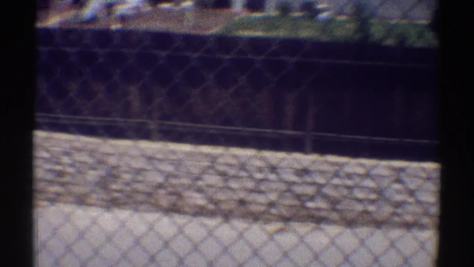 Woodland Hills residential roofline and fencing viewed past a dark foreground post in 1969 8mm footage.