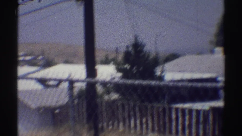 Woodland Hills residential rooftops, utility pole, shrubs, and fencing in a handheld 1969 home-movie frame.