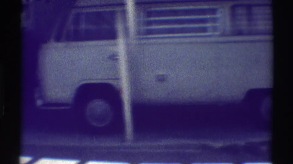 White Volkswagen-style Kombi van parked along a Woodland Hills residential exterior in a soft, grainy 1969 home-movie frame.