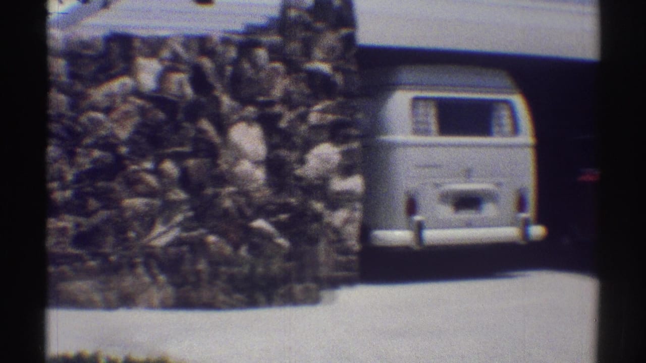 Stone wall and driveway beside a garage with a white van partly visible.